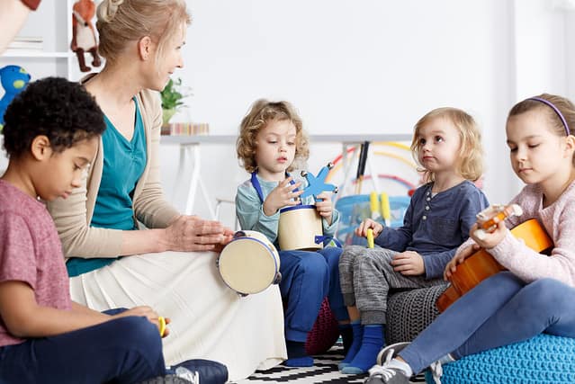 Four preschoolers having fun in kindergarten playing the instruments