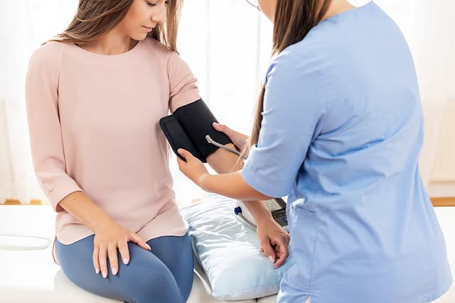 Young woman having her blood pressure taken by a nurse