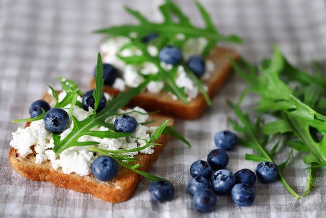 Selective focus. Cottage cheese toast with blueberries and arugula. The keto diet. Keto toast. Bruschetta with cottage cheese.