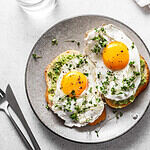 Avocado Egg Sandwiches and coffee for healthy breakfast. Whole grain toasts with mashed avocado, fried eggs and organic microgreens on white table. Healthy breakfast ideas for busy mornings.