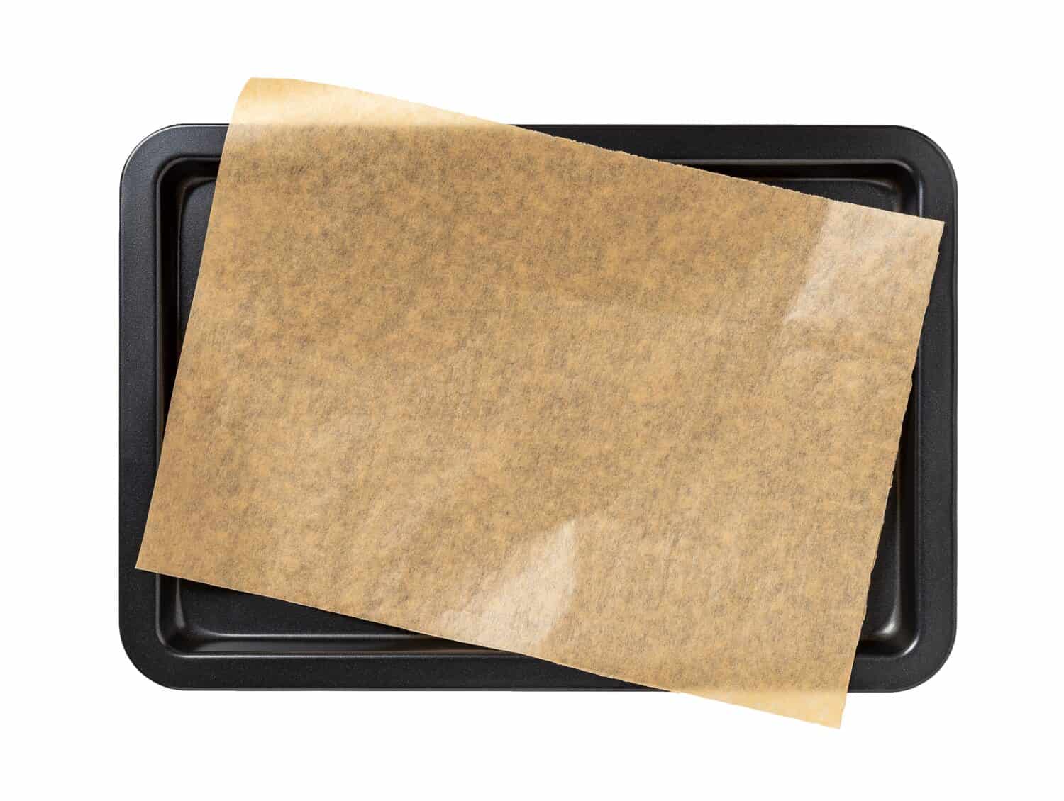 Baking sheet with brown parchment paper isolated on a white background. Empty oven tray for baking and roasting. Rectangular baking pan for food design. Nonstick kitchen utensils. Top view.