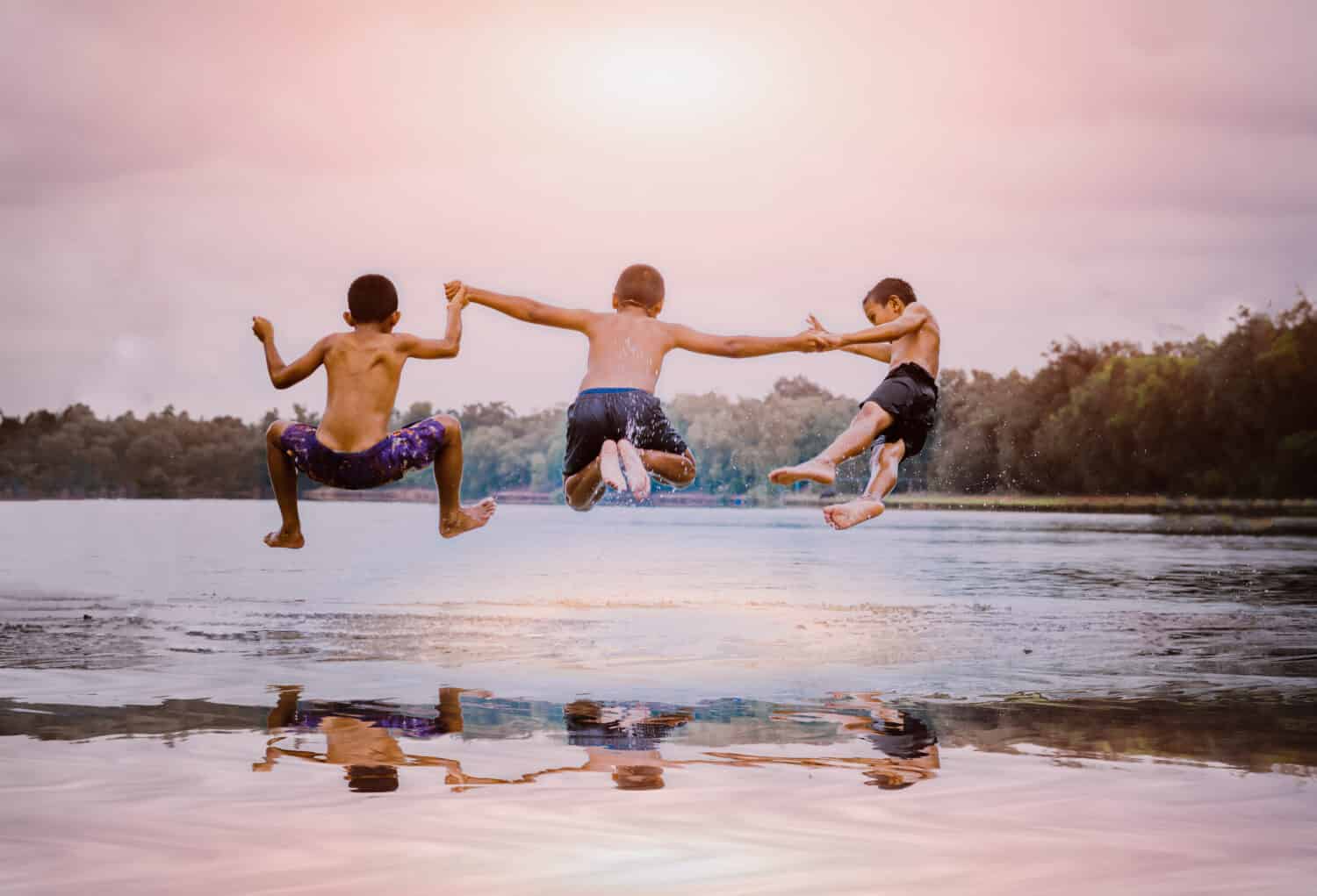 young boys jumping into the lake.