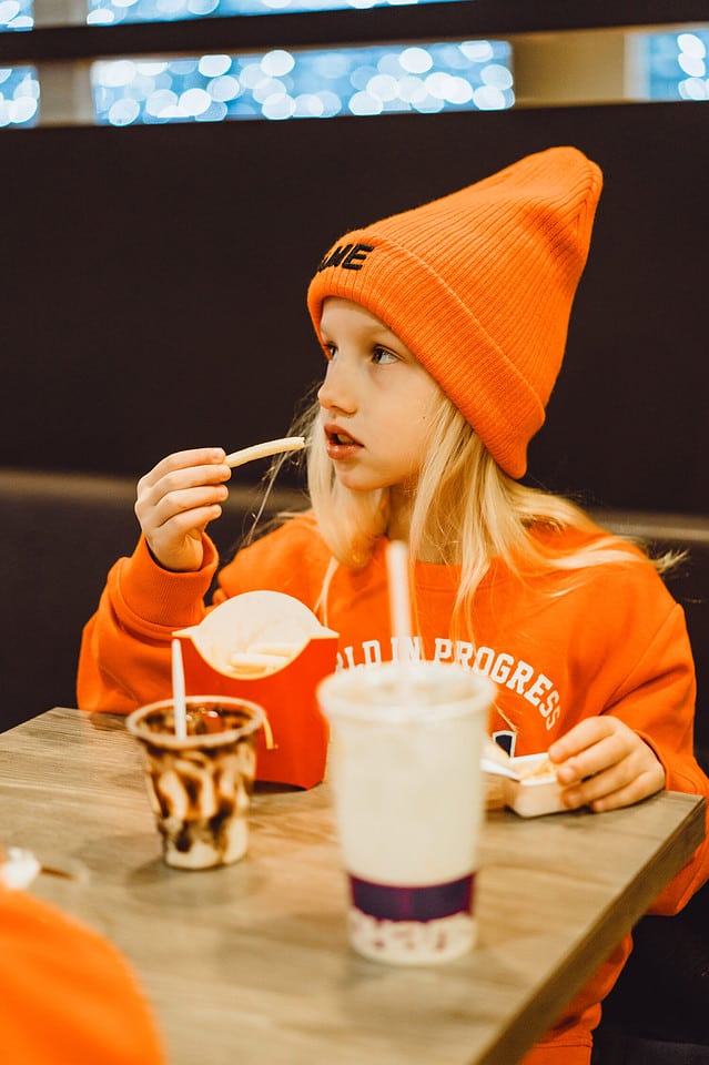 children at mcdonald's. Little girl eats french fries and drinks a cocktail in a cafe.