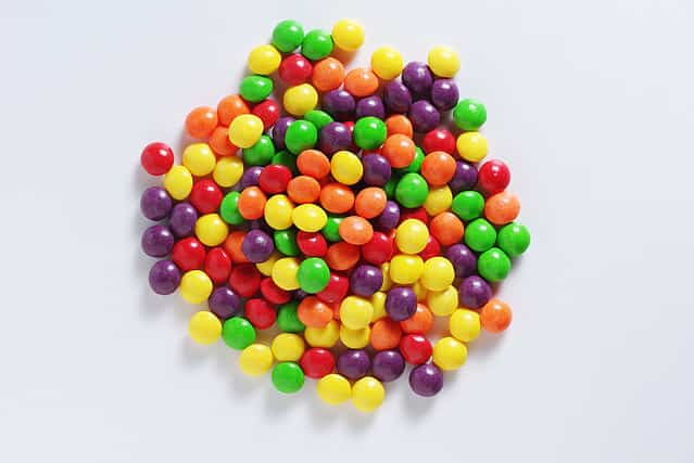 Colorful skittles candies on a white background, top view