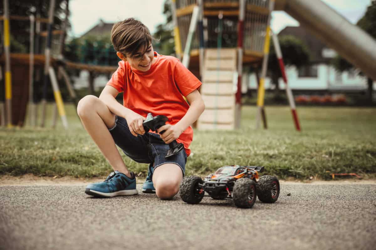 teen boy with electric remote control car toy play outdoor on sidewalk and have fun while enjoy his childhood