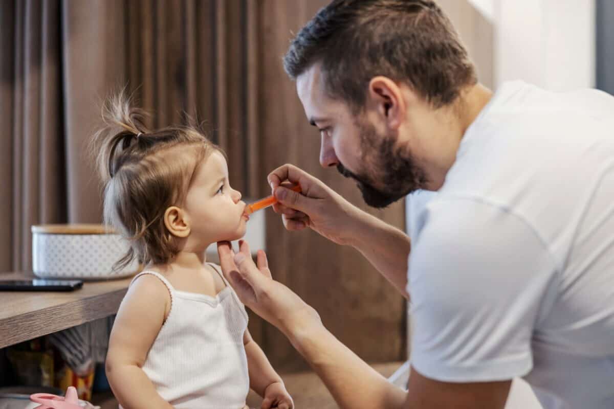 A tender father is giving a medicine to his baby girl.