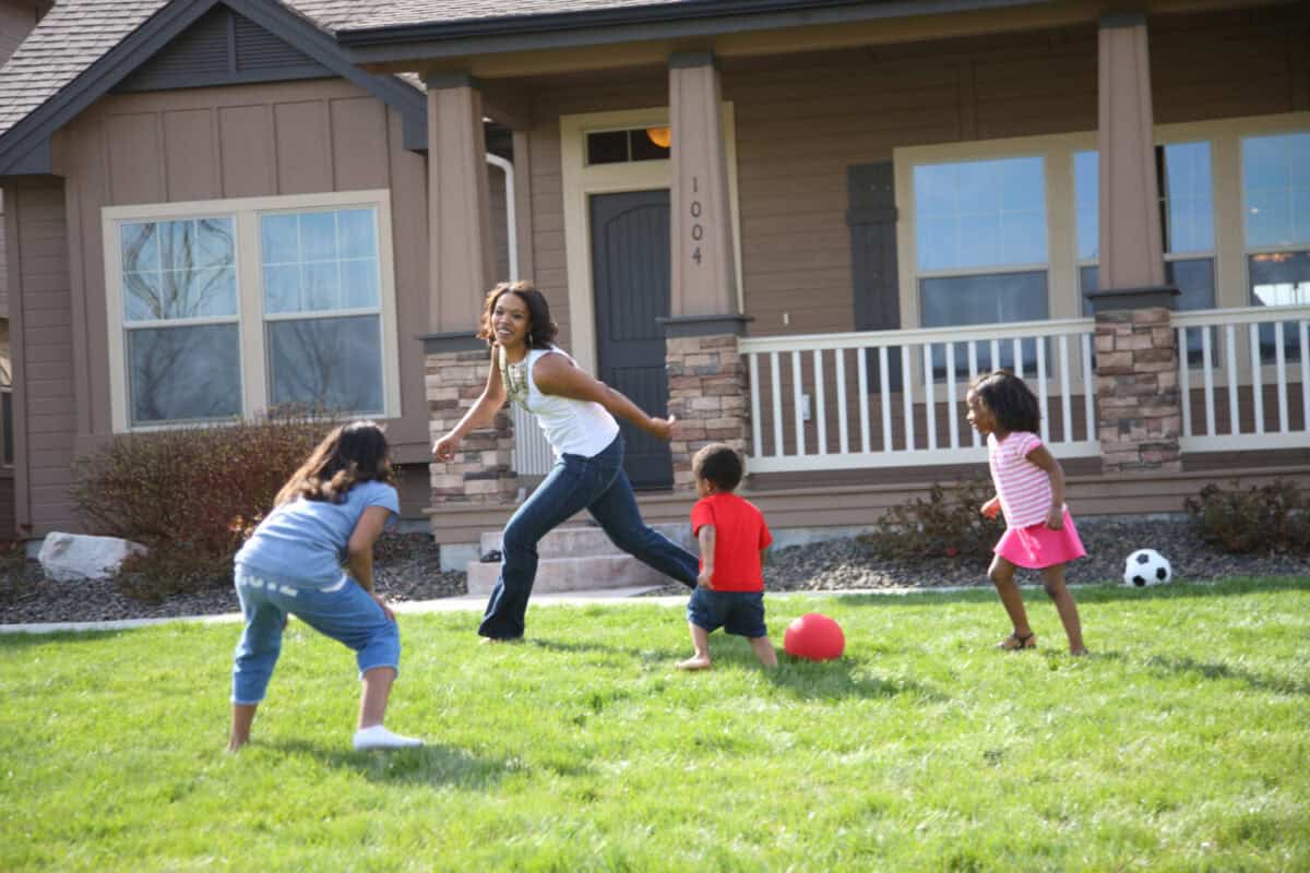 Mother and children running and playing in front yard