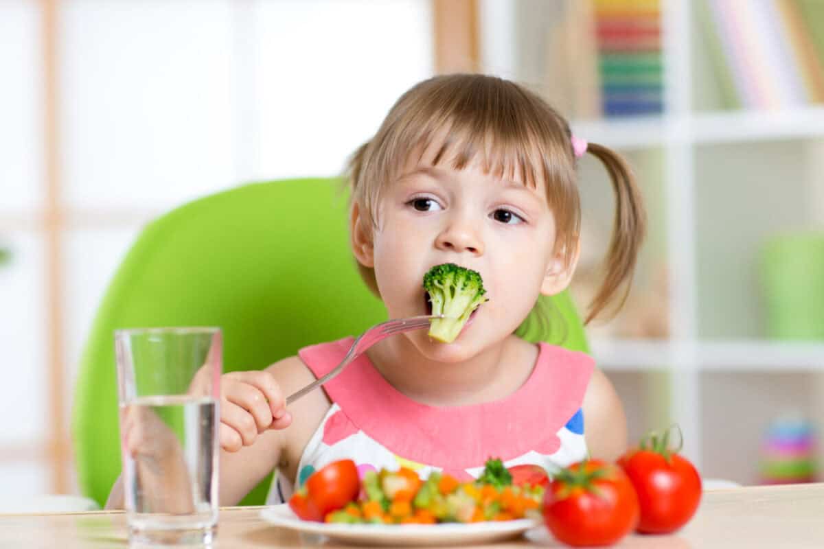 Child little girl eats vegetable salad using fork