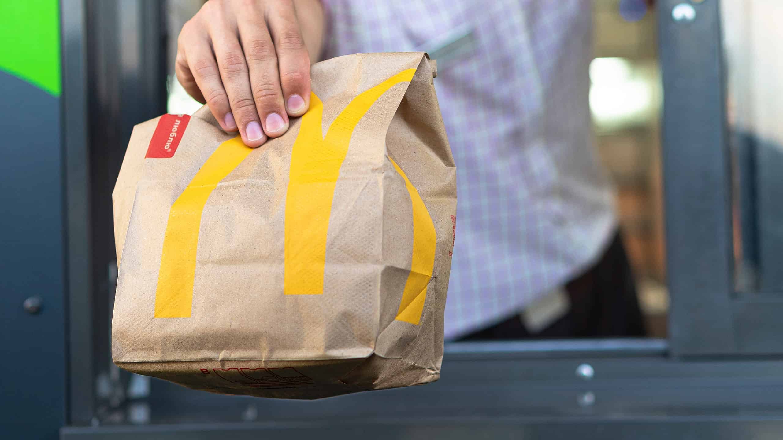Man hands fast food bag out the drive-thru window