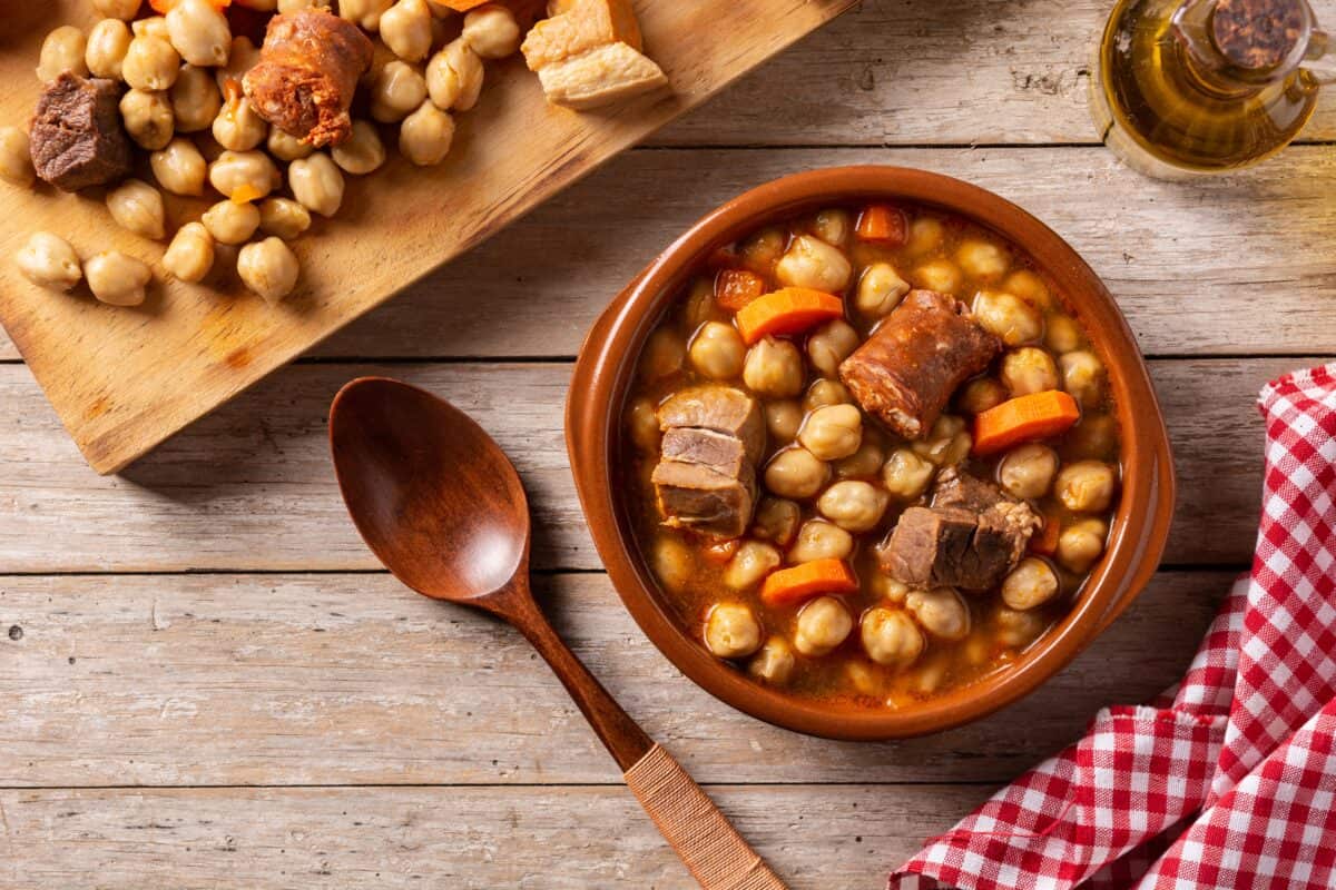 Traditional Spanish cocido madrileño. Chickpea stew on wooden table