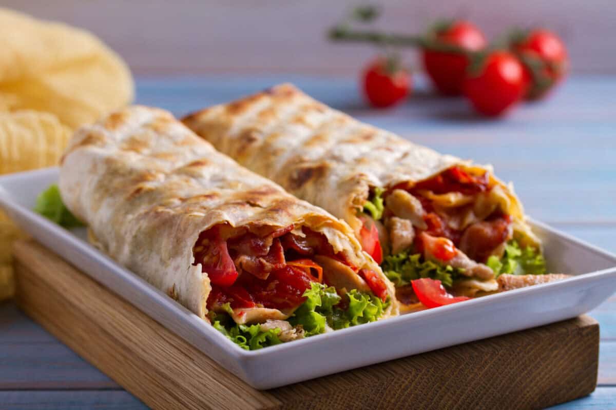 Chicken caesar salad wraps with bacon, tomatoes, lettuce and cheese. Tortilla, burritos, sandwiches twisted rolls
