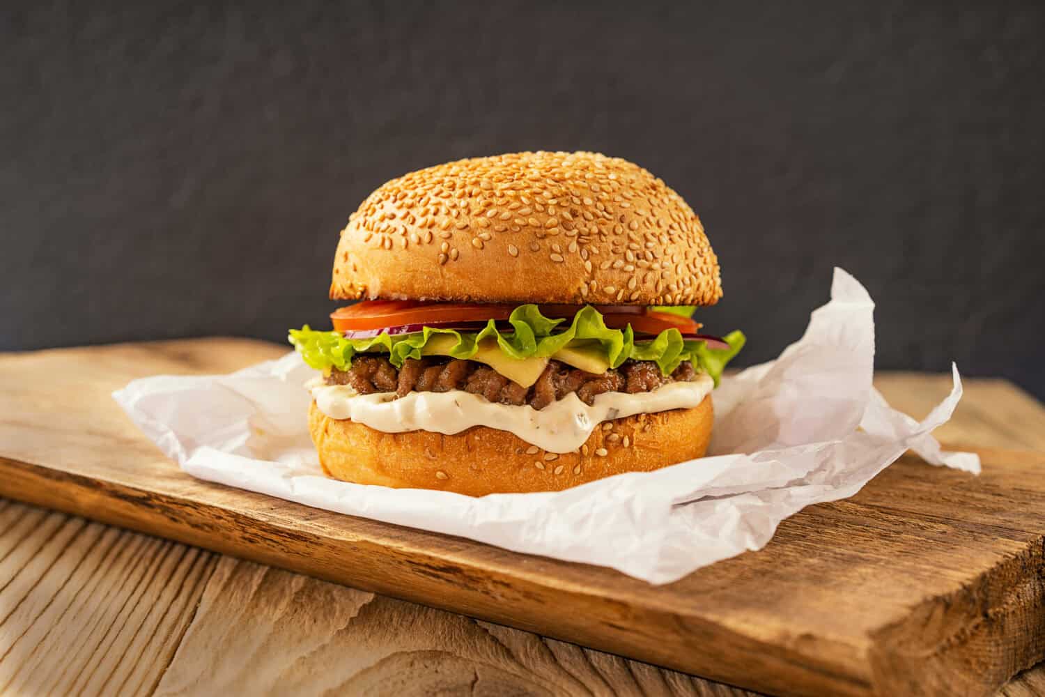 Homemade delicious hamburger on a wooden table, rustic style. Fast food. Space for the text.