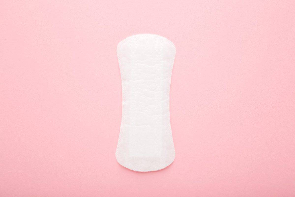 New white panty liner on light pink table background. Pastel color. Closeup. Female daily hygiene.