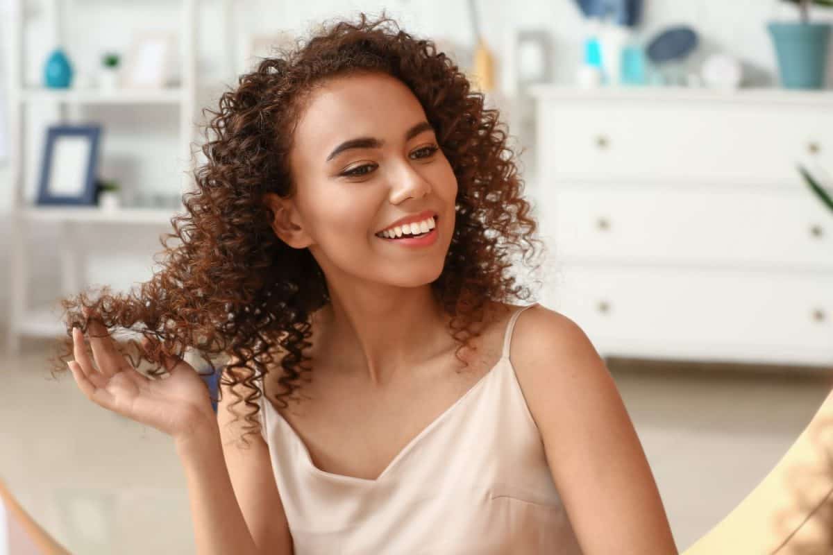 Young African-American woman with healthy hair in bathroom