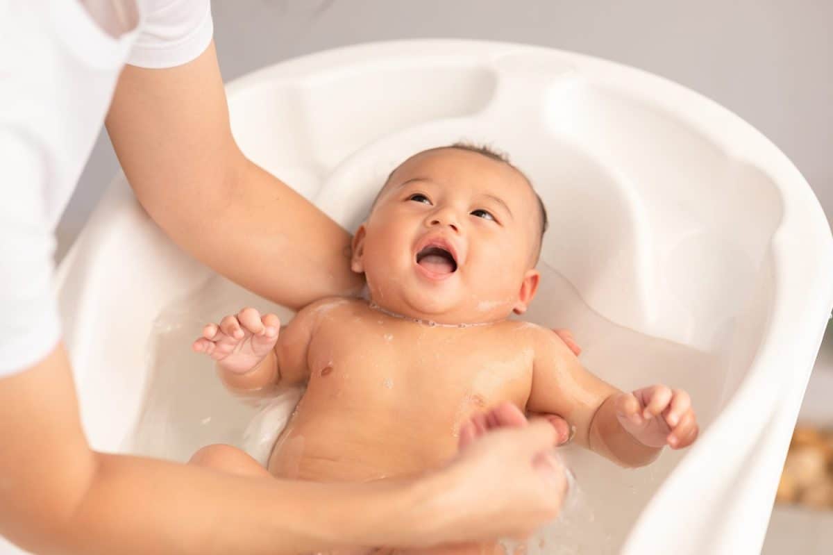 Calm of asian newborn baby bathing in bathtub.mother bathing her son in warm water.Happy adorable newborn infant smile in tub relax and comfortable.Newborn baby care concept. Treatment options for a constipated baby