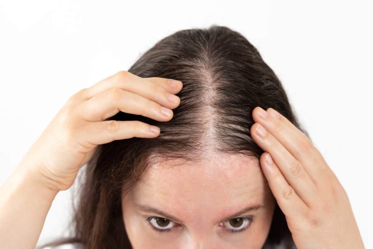 Close-up of woman controls hair loss and little volume with fine hair against white background shampoos for extremely dry hair