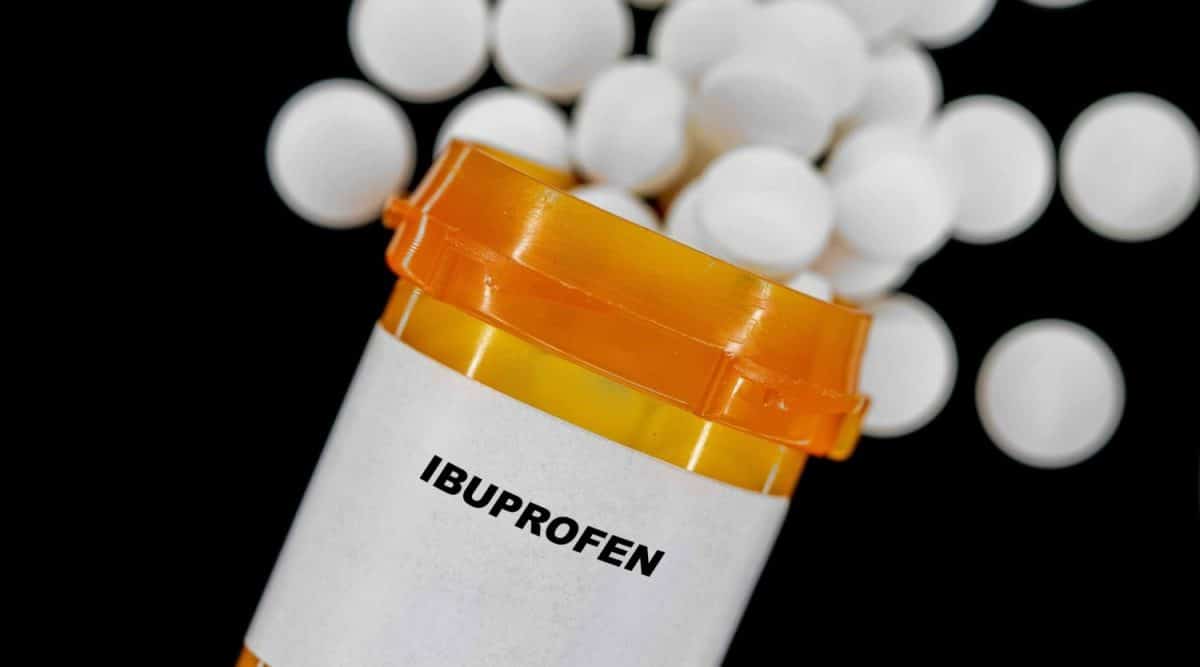 Ibuprofen Rx medical pills in plactic Bottle with tablets. Pills spilling out from yellow container. Treatment for strep throat