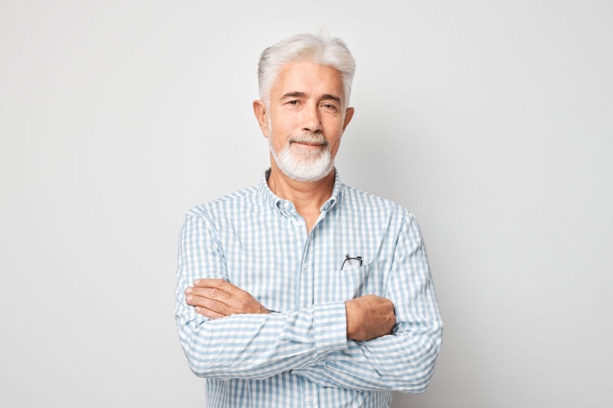 Portrait of confident mature businessman with serious face and gray hair isolated on studio background. Good looking 60 year old man, boss in business casual. Shampoo for gray hair on man