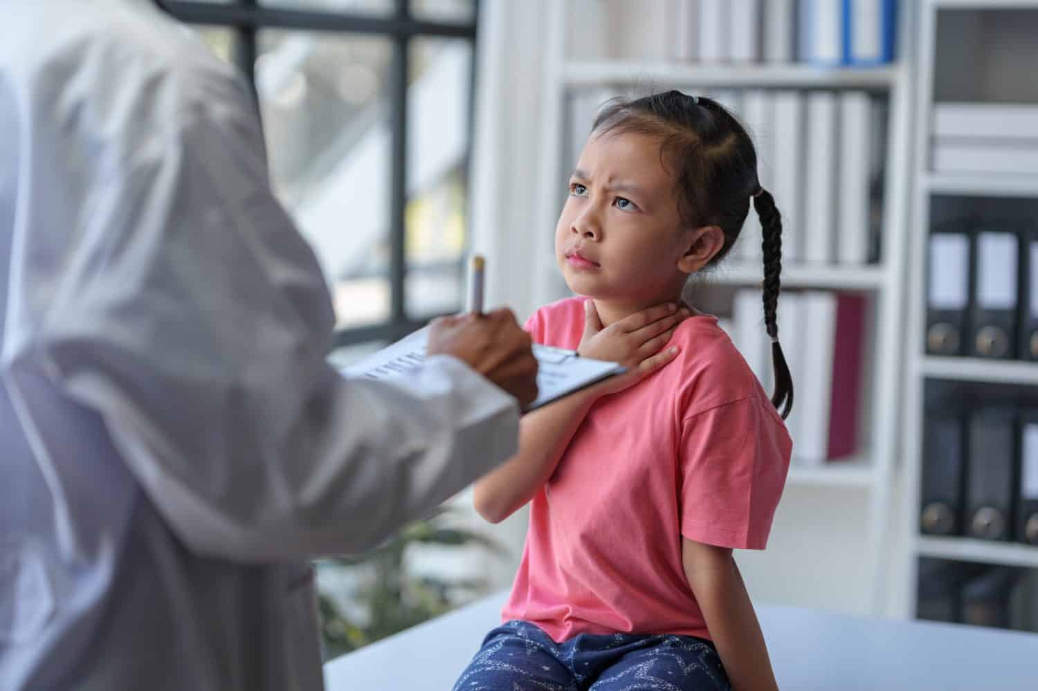 A female doctor stands with a file and asks about the history of young patients who come for treatment. have a headache Sore throat while sitting on the table planning treatment and care.