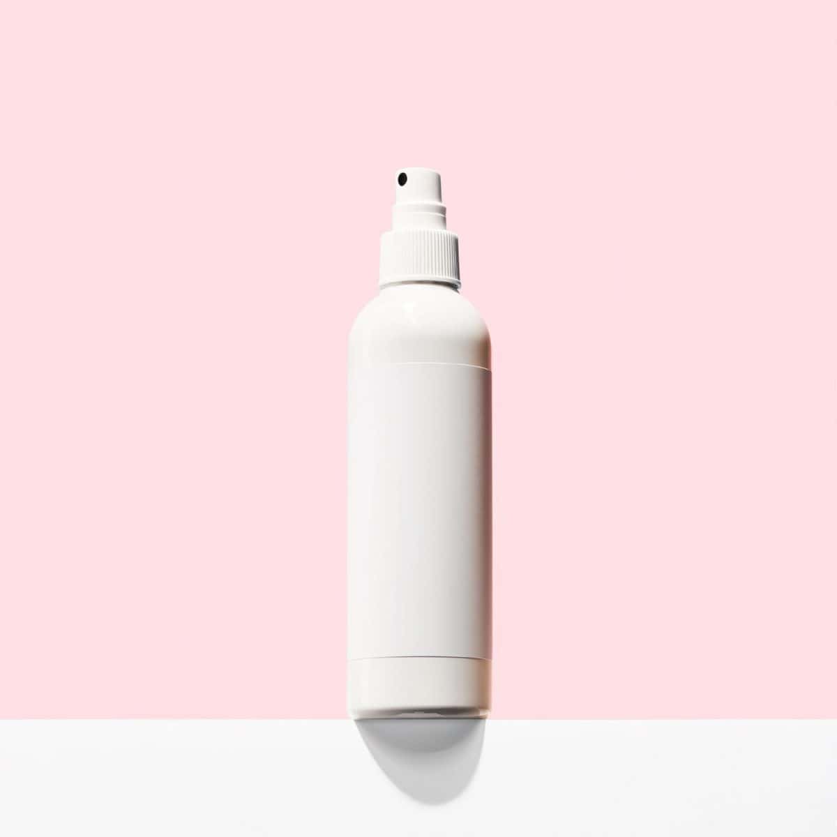 Empty bottle without labels on pink background. Mockup for cosmetic spray bottle, like mineral spray or hairspray. Front view, space for design. White spray bottle for various cosmetic products. Best treatment options for diaper rash