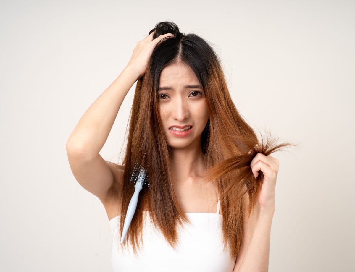Young asian woman having problems with her hair Thin damaged dry hair falls out easily and is not healthy have to cut off. Standing on isolated white background. Shampoos for Extremely Dry Hair