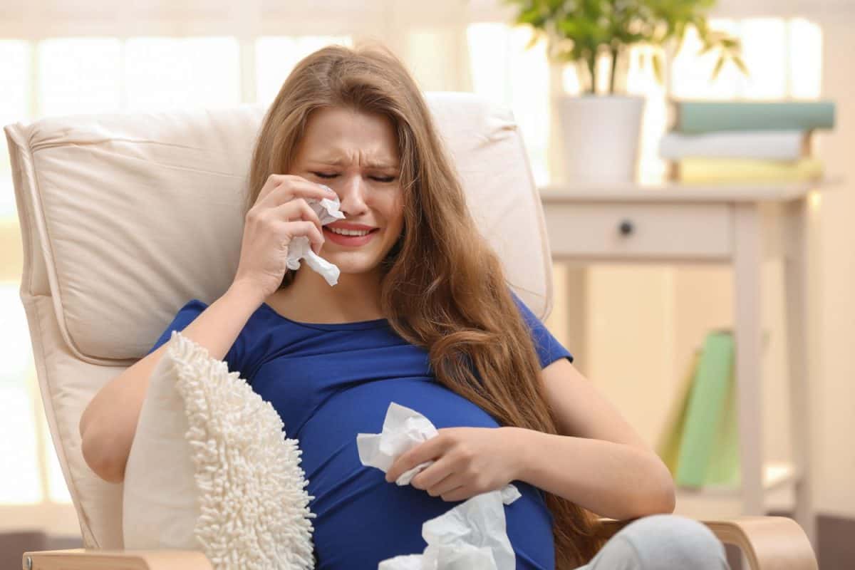 Emotional pregnant woman sitting in arm chair and crying. Pregnancy hormones concept pregnancy symptom's none warns you about