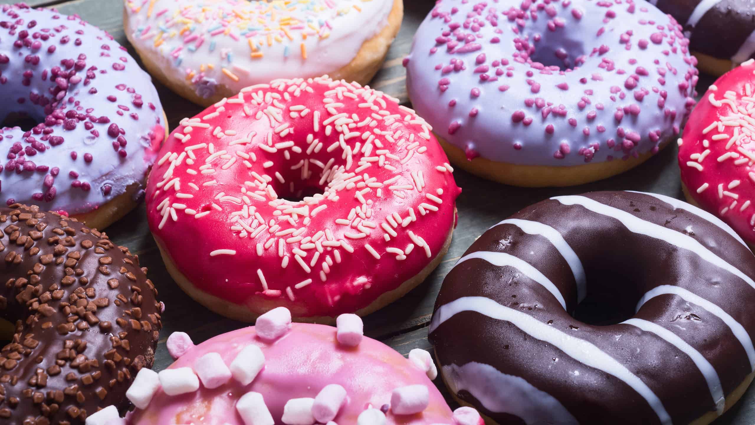 assorted donuts with chocolate frosted, pink glazed and sprinkles donuts.