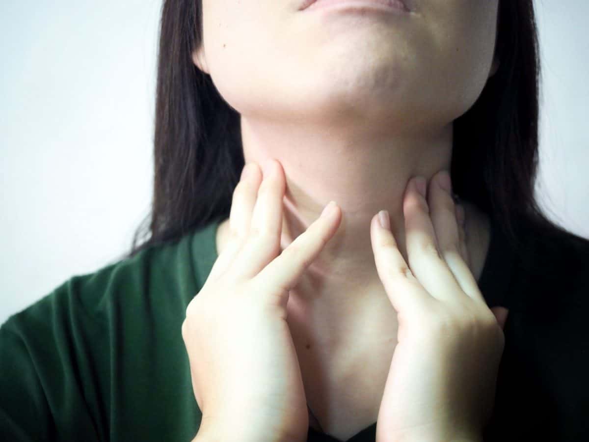 Close up Asian woman hand caught on the neck With a sore throat on a gray background With the concept of health care and medical