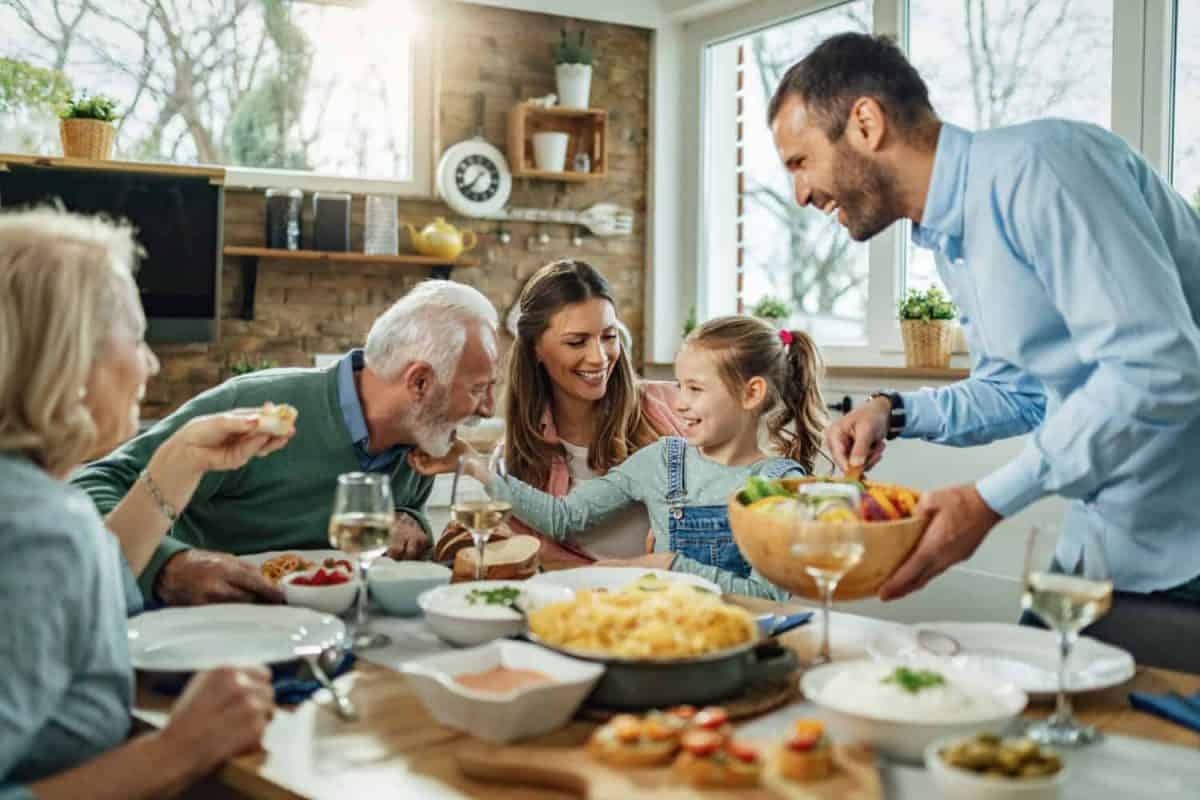 Happy multi-generation family gathering around dining table and having fun during a lunch.