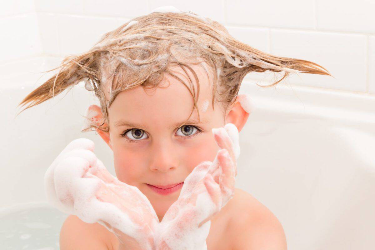 Young girl in bath with funny hair and bubbly hands. The best treatment options for lice.