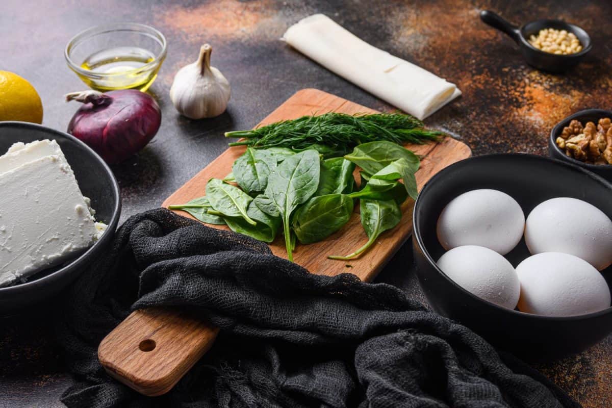 Traditional greek spanakopita ingredients filo spinach eggs feta side view.