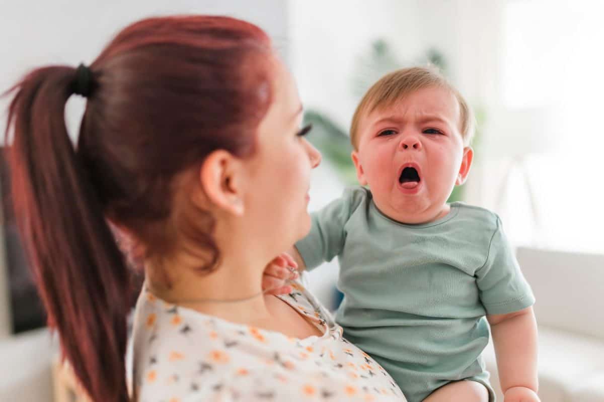 A mother holding child baby on the living room. The baby is sick having some cough