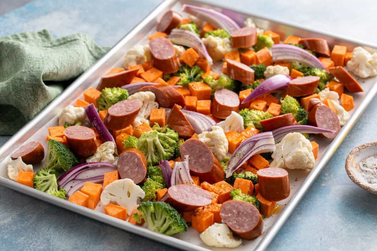 Sheet pan dinner with sausage and vegetables ready to be roasted with broccoli and cauliflower