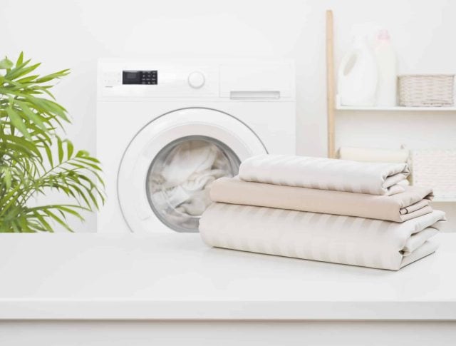 Stack of clean bedding sheets on blurred laundry room background