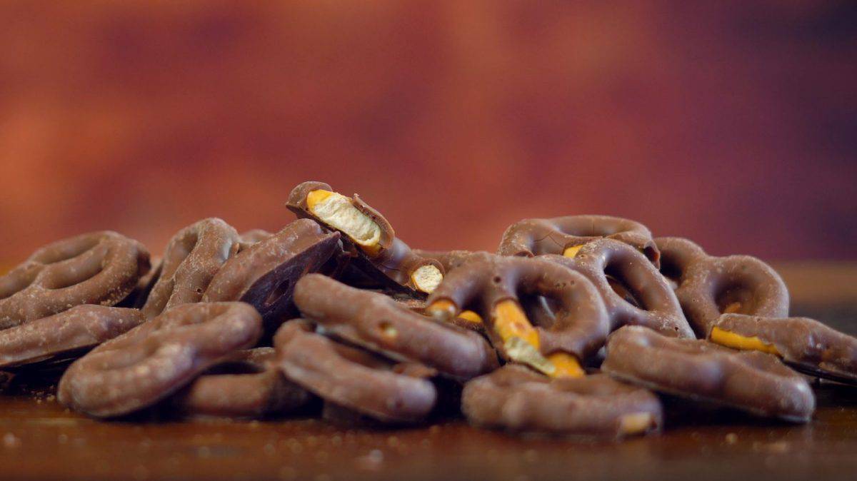 Sweet and salty chocolate covered pretzels snacks macro close up on rustic wood background with copy space.