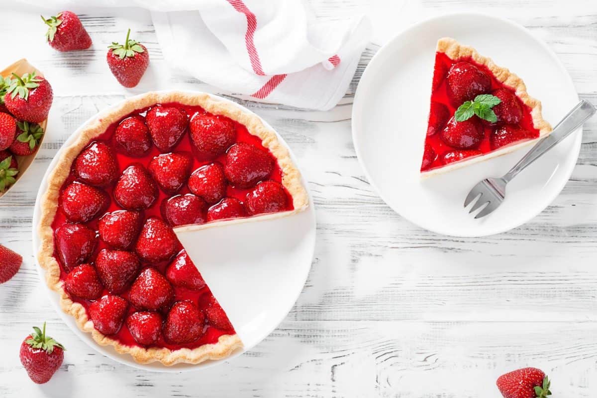 Delicious strawberry tart on white wooden background, top view