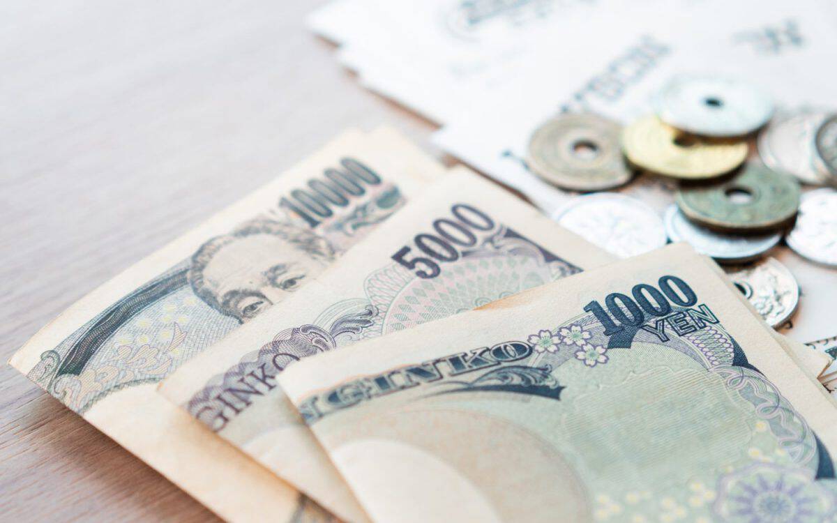 Closeup: Wads of Japanese banknotes 500, 1000, 10000 yen and small coins with sale slips from the convenience store lay on the table. Japan, Tax free for tourist, Cost of living, Expenses, Tokyo 2020.