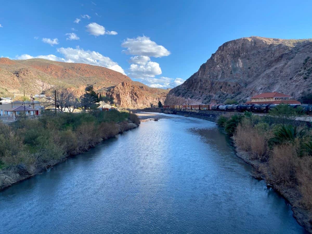 The San Francisco River in Clifton, Arizona with mountains, and cloudy blue sky.