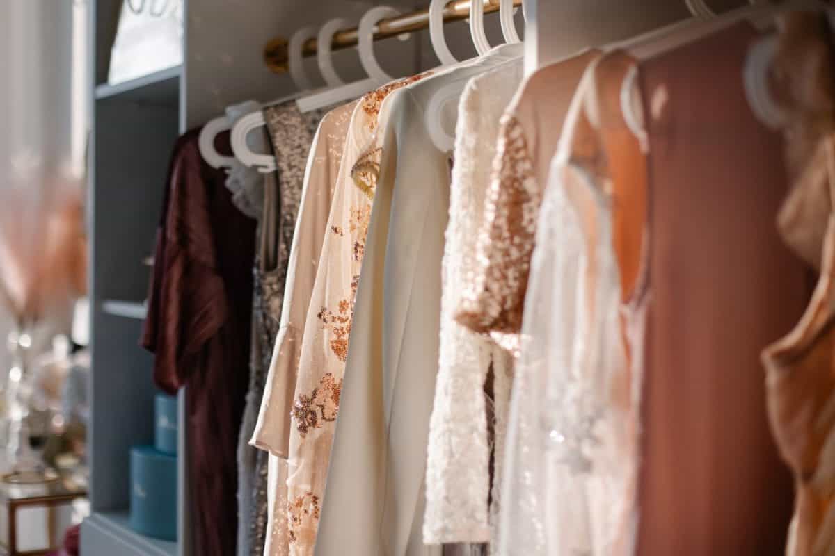 Beautiful female wardrobe. A lot of party dresses hanging on hangers in closet. Vintage clothing rental concept. Women's space. Large selection of various clothes. Small boutique showroom fashion shop