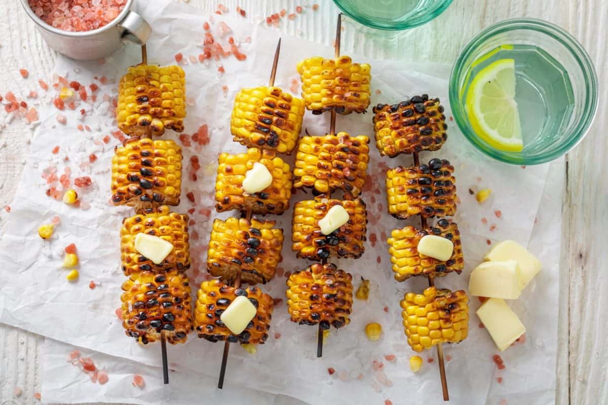 Homemade grilled corn cob with melting butter on stick. Corn grilled with butter on bonfire.