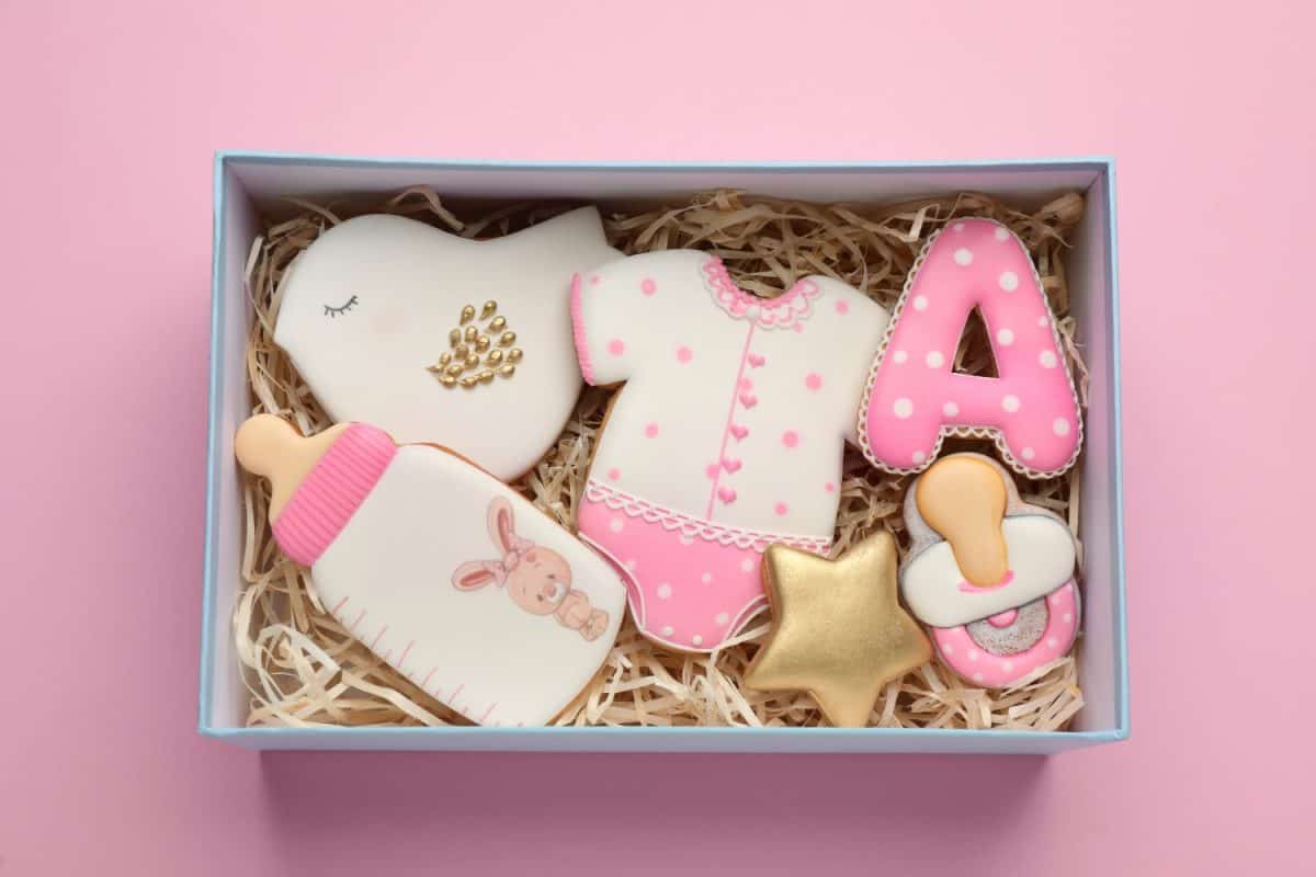 Set of baby shower cookies in gift box on light pink background, top view. A-Z Baby Names That Your Child May Regret Being Named