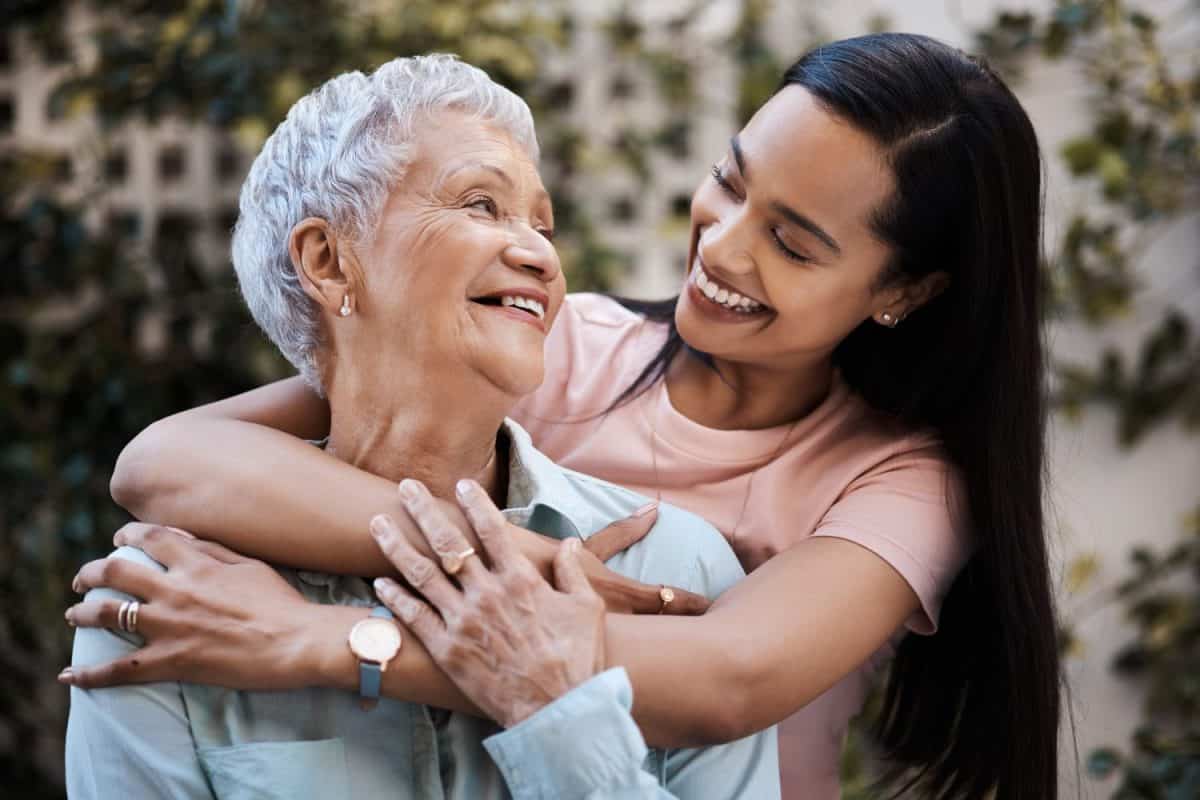 Happy, hug and loving of a mother and woman in a garden on mothers day with care and gratitude together. Smile, family and an adult daughter hugging a senior mom in a backyard or park for happiness