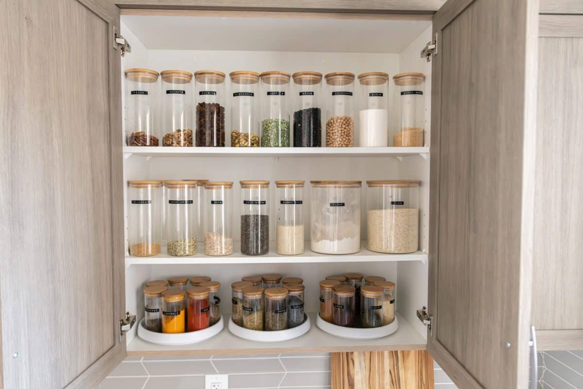 Neatly organized labeled food pantry in a home kitchen with spices grains flour rice sugar nuts