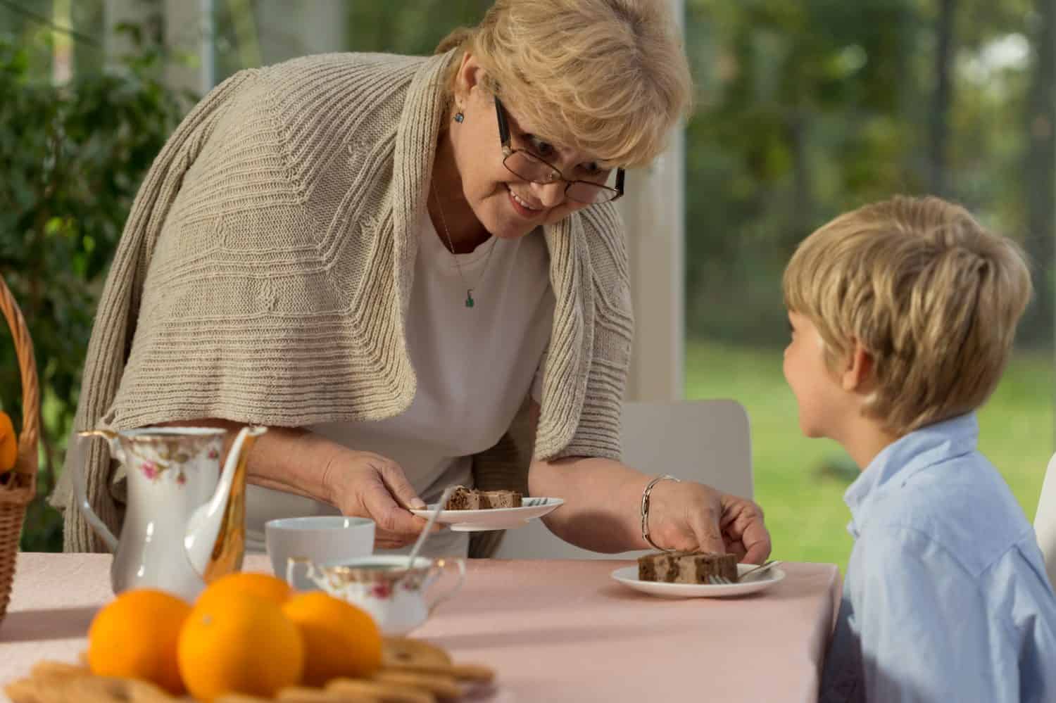 Grandson and his grandma dishing up homemade cake