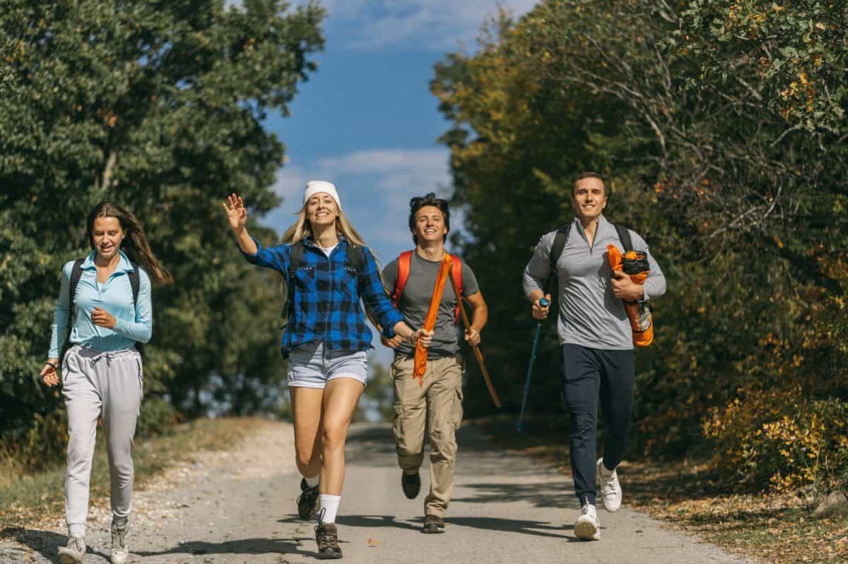 Young males and females hikers running on the street between the mountains they were hiking. The best U.S. National parks for hiking.