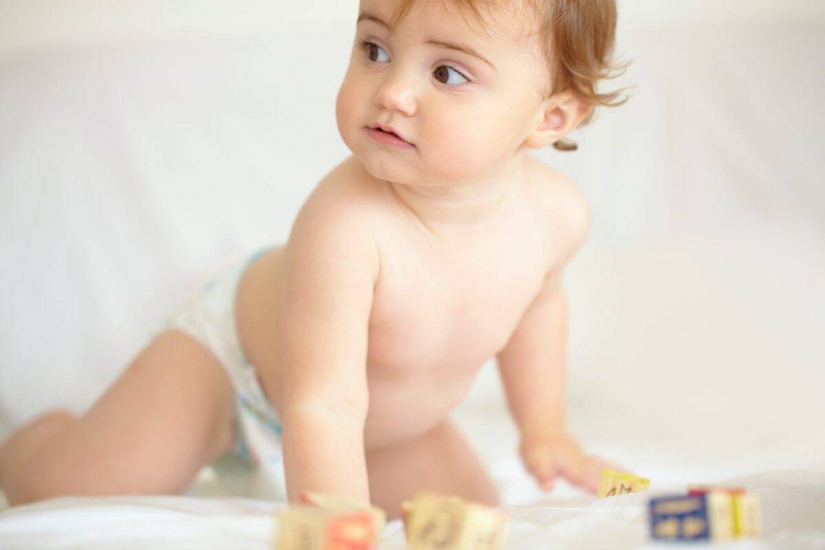 Baby, building blocks and playing on bed, education and learning for child development in bedroom. Sensory, alphabet and english or letters, care and toys for growth, coordination and cognitive skill