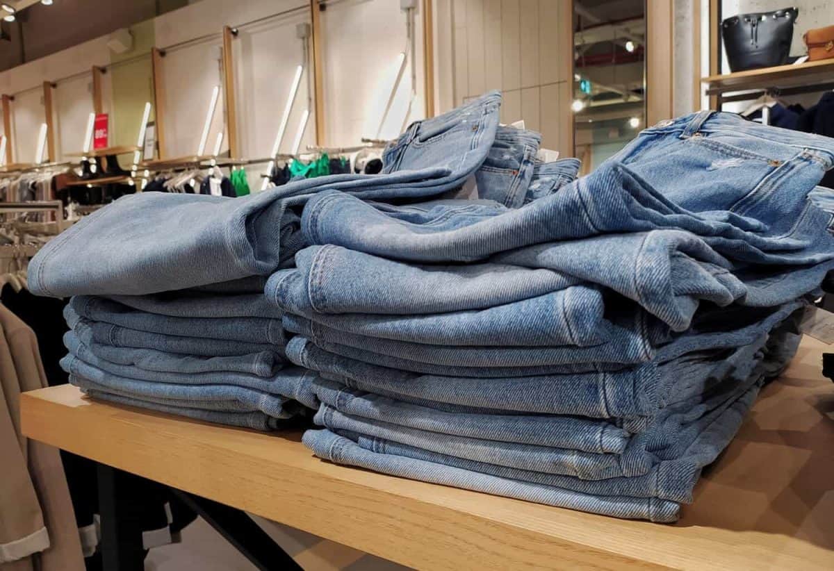 Stack of blue jeans in the store for sale. Jeans trousers stack in a clothing store in the shopping mall. Concept of buy, sell, shopping and jeans fashion. Textile industry. Retail trade