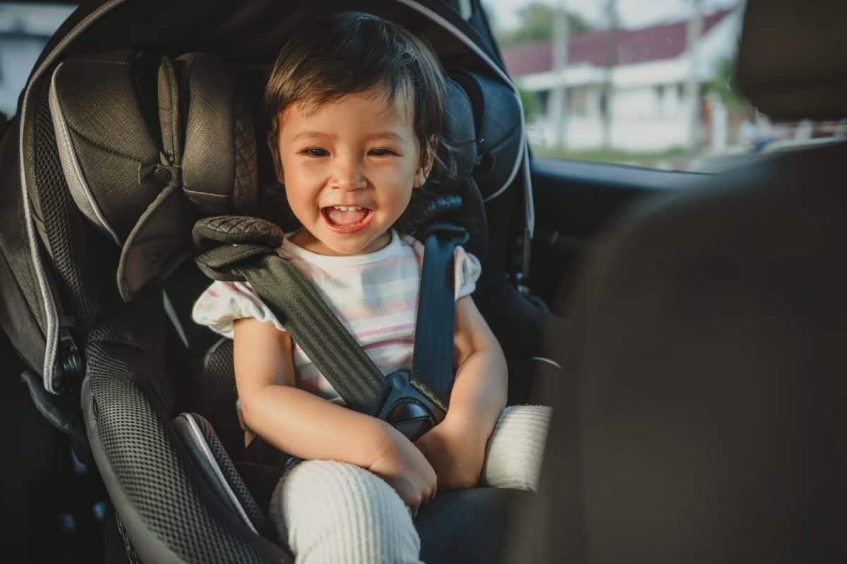 happy toddler girl sitting in a car seat, safety baby chair travelling