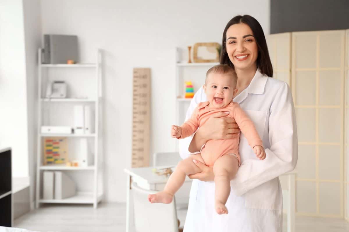 Portrait of female pediatrician with little baby in clinic