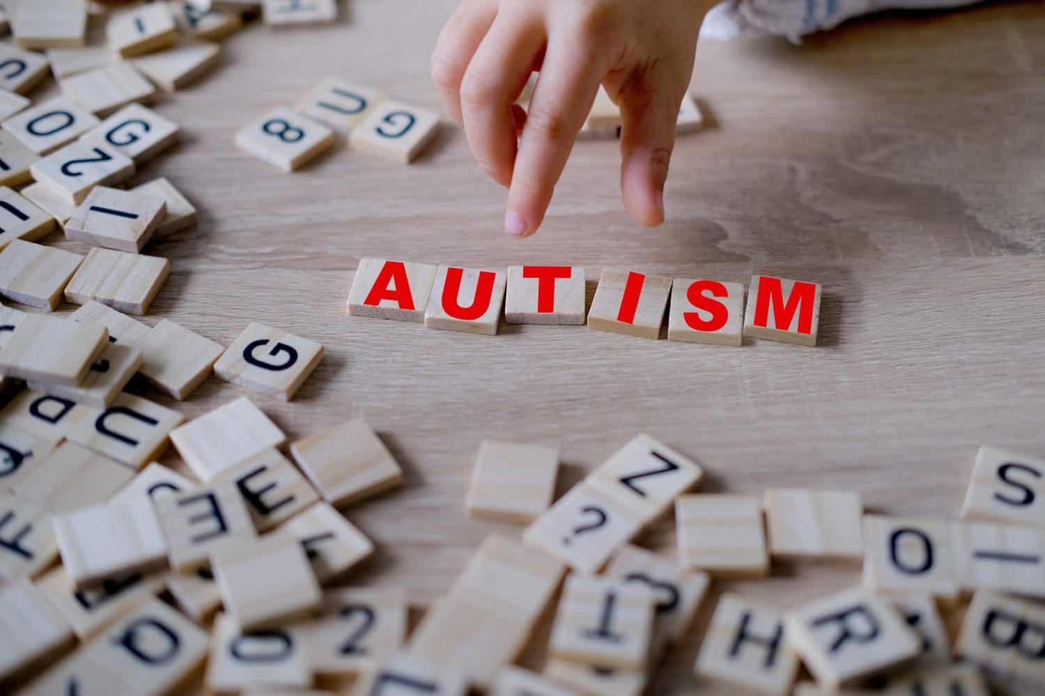 child's hand complete word "AUTISM," symbolizing importance of early diagnosis and intervention for children with autism, self-acceptance and embracing neurodiversity